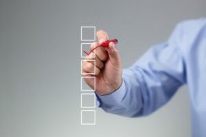 Blank checklist on whiteboard with businessperson's hand drawing a red check mark in one checkbox